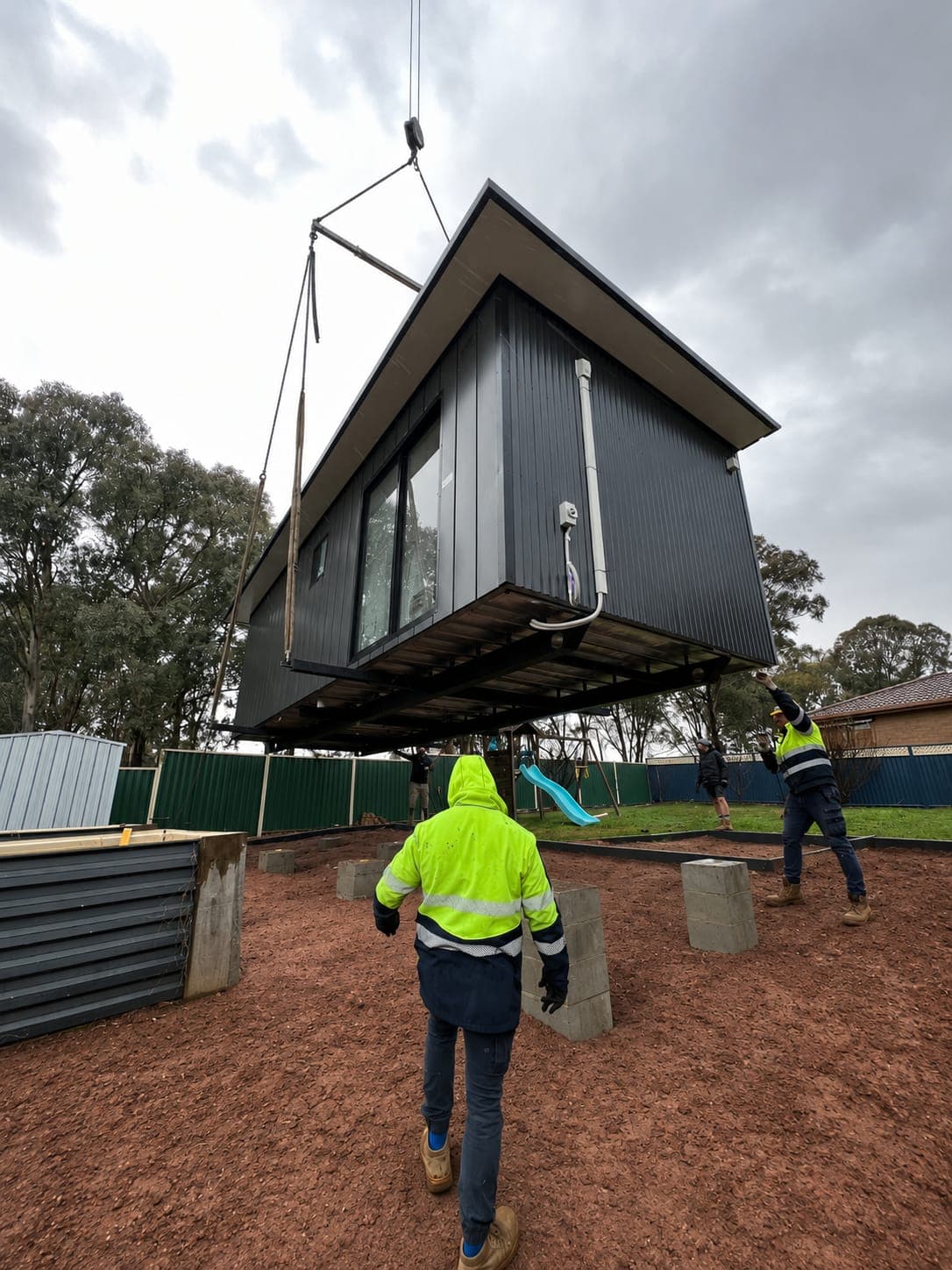 Modlux crew lowering a modular home onto its footings on site