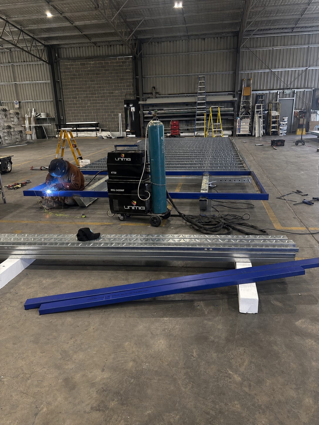 A Modlux fabricator welding a steel chassis on the factory floor
